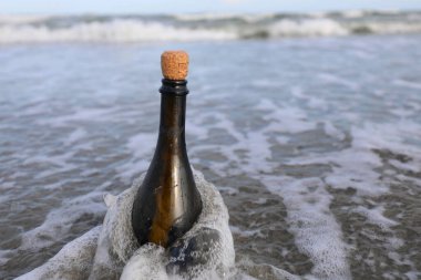 İçinde gizli bir mesaj ya da deniz kenarında bir hazine haritası bulunan bir mantarlı cam şişe.