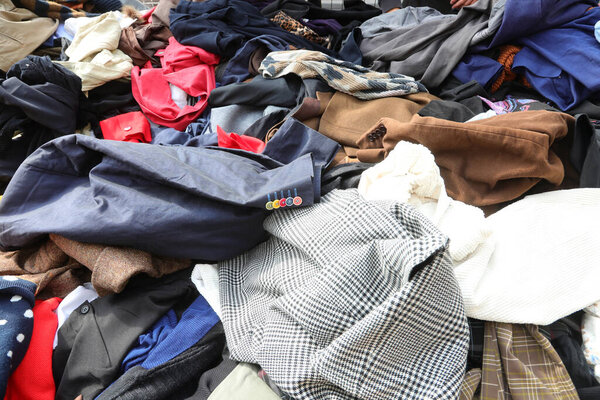 Messy pile of numerous used garments clothing and attire on an outdoor flea market stall