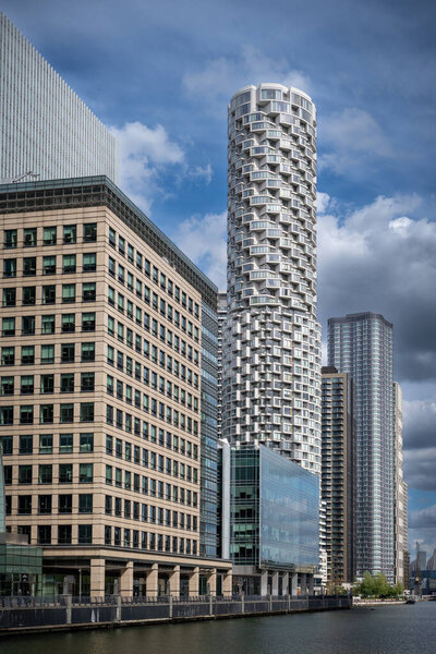The modern skyline of Canary Wharf in London, England, captured on a bright day with blue skies and scattered clouds, showcasing its iconic skyscrapers and financial district architecture.