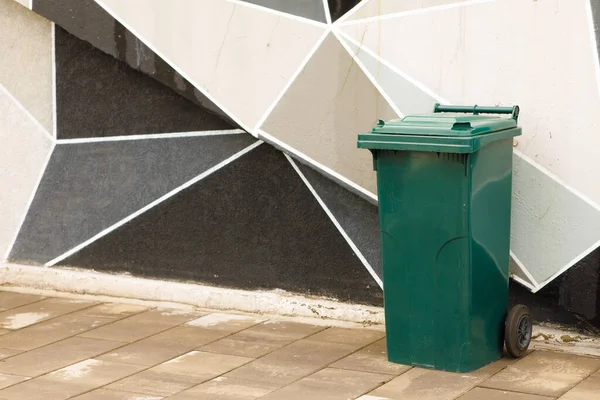 green garbage can near the wall. High quality photo