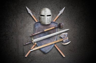 Siyah beton arka planda şövalye silahları.