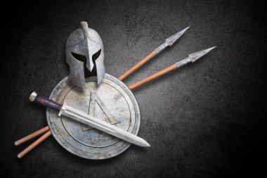 Spartalı miğfer kılıç kalkanı ve soyut siyah duvar arka planında iki mızrak.