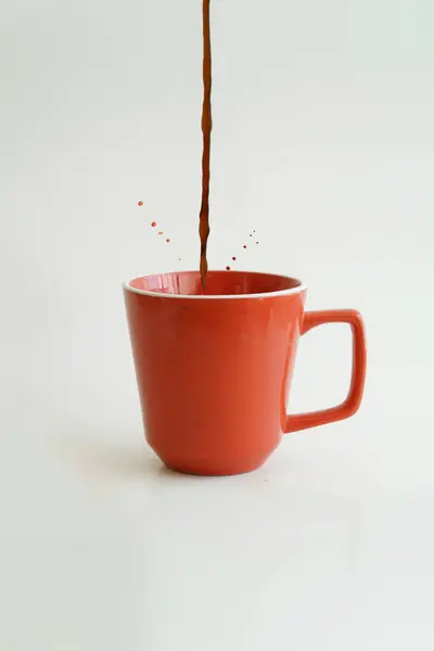 Red cup of coffee with one drop against a white background