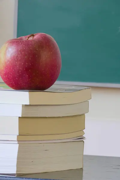 Roter Apfel Sitzt Auf Einem Stapel Bücher Hintergrund Eine Tafel lizenzfreie Stockbilder