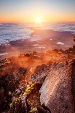 Pico Dağı, Azores, Portekiz 'de kayaların ön planında parlayan güneşin manzarası