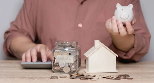 男は貯金して貯金箱に入れるためにお金を計算している 将来の住宅購入のためのお金を節約し 退職後に将来的に使用するためのアイデア 家族費 — ストック写真