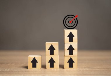 Pazarlama hedefleri belirleme fikri. Masanın üzerindeki tahta blokta hedefin tepesini gösteren bir ok var. Pazarlama için hedefler ve gelecekteki ihtiyaçlar belirleyin. 