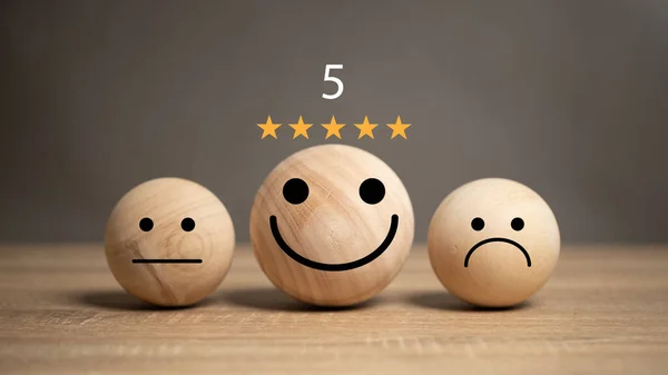 The concept of service satisfaction Smiley face ball with 5 star rating placed on wooden table Satisfaction with the service received from the service provider. Polls, Ratings, score, questionnaire.