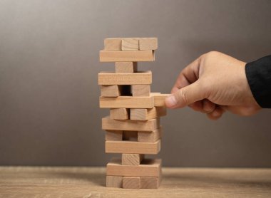 İş planlama, risk ve strateji. Adam ahşap bloklardan yapılmış iş modelini elinde tutuyor. Alternatif risk konsepti, iş planı ve iş stratejisi. Sigorta konsepti. Şirket konsept riski.