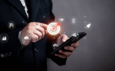 İş dünyasının amacı ve hedefi olan akıllı telefonu elinde tutan iş adamı, kurumsal kalkınma ve küresel işletme liderliği, başarı ve strateji. iş ve pazarlama planı hedef kavramı. 