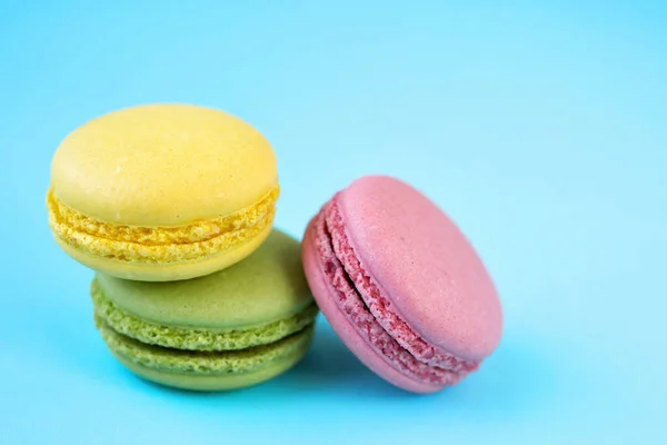stock image French traditional green, yellow and pink macarons on pastel blue background