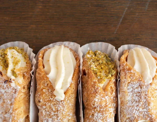 Top view of four cannoli freshly display in nice paper on a wooden background