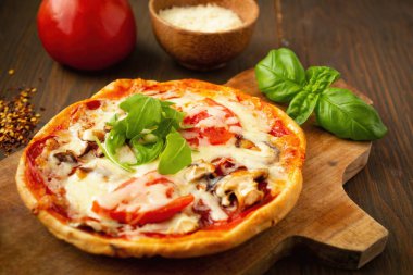 Domatesli, mantarlı, biberli, fesleğenli ve roka arkaplanlı ev yapımı pizza.