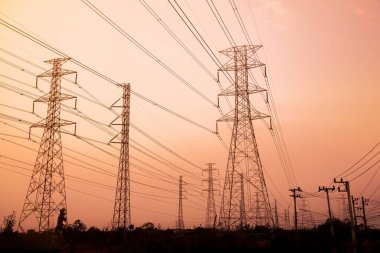 Gökyüzü günbatımı arka planında yüksek voltaj direği.