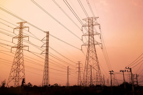 Gökyüzü günbatımı arka planında yüksek voltaj direği.