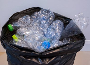 Siyah çöp torbalarındaki plastik şişeler geri dönüşüm için alınmayı bekliyor..