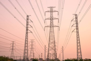 Gökyüzü günbatımı arka planında yüksek voltaj direği.
