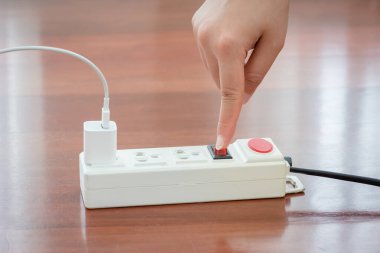 Elektrik prizini açmak için kırmızı düğme kullanarak elektrikçinin elinin yakın plan görüntüsü, elektrik prizindeki kırmızı düğmenin insan parmağını kapatarak elektrik tasarrufu..