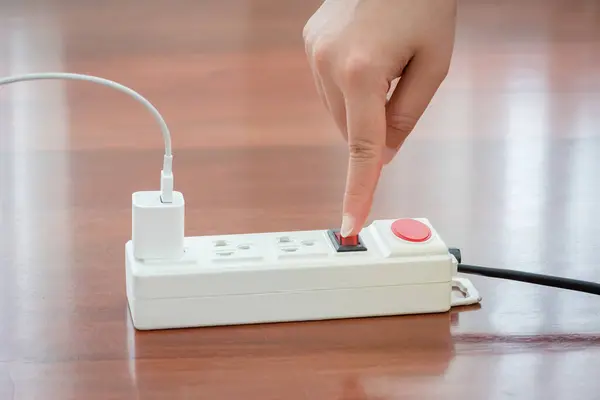 Close-up of electrician\'s hand using red push button to turn on the power strip,Save electricity by turning off the human finger on the red button on the electrical plug.