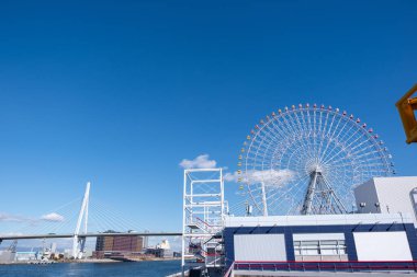 Osaka Akvaryumu Kaiyukan Osaka, Japonya 'daki eğlence parkında mavi gökyüzünün arka planında dönme dolap..