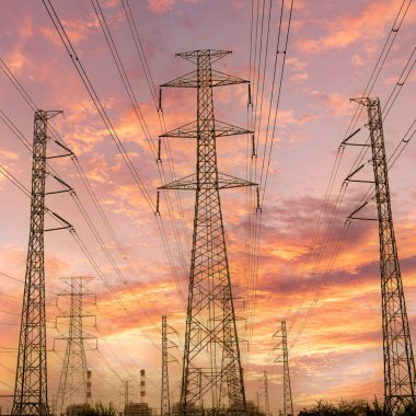 Gökyüzü günbatımı arka planında yüksek voltaj direği.