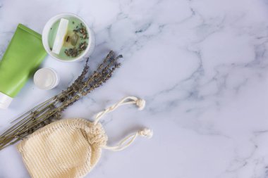 Üzerinde yeniden kullanılabilir pamuk pedleri olan bir çanta mermer arka planda makyaj çıkarıcıları.