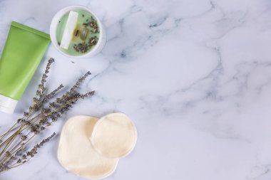 Üzerinde yeniden kullanılabilir pamuk pedleri olan bir çanta mermer arka planda makyaj çıkarıcıları.