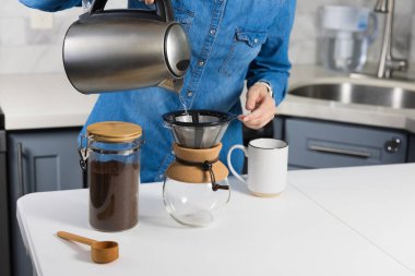 Evde kahve üzerine kahve döken bir kadın.