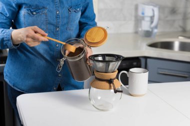 Evde kahve üzerine kahve döken bir kadın.