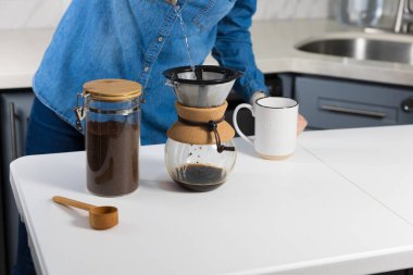 Evde kahve üzerine kahve döken bir kadın.