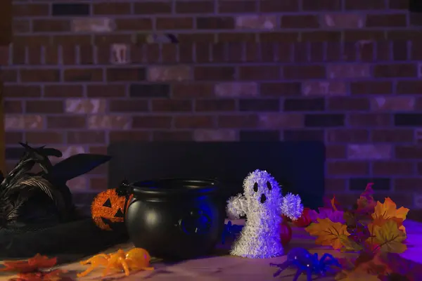 Spooky Halloween decorations on the table with a pumpkin and a witch cauldron