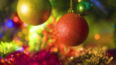 Şenlikli süslemelerin ve çelenklerin arka planında üç parlak Noel süsü asılı duruyor. Yeni yıl tatili kavramı, Noel. Seçici odak.