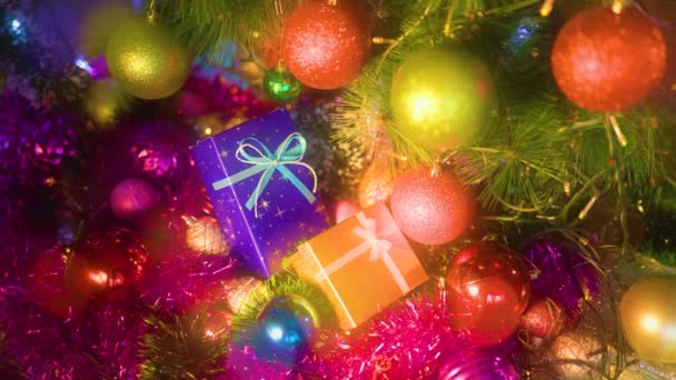 青と黄色のギフトボックスは 輝く光 ボケの背景にあります 様々な色のクリスマスの装飾はお祭り気分を作成します 選択的焦点 — ストック動画