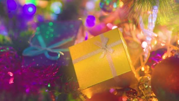 クリスマスツリーの下に横に弓を持つ背景の黄色と青のボックスをぼやけている 新年のチンセル クリスマスの装飾 休日や幸福 選択的焦点 — ストック動画