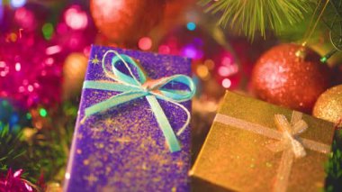 Fiyonklarla bağlanmış iki hediye kutusu için bulanık arkaplan. Üzerlerine altın pullar dökülüyor. Yılbaşı süsleri ve Noel süslemeleri şenlikli bir ortam yaratır. Seçili odak.