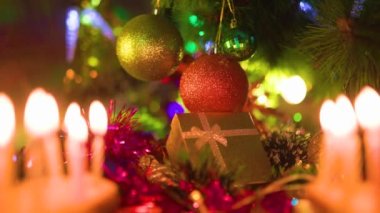 Bulanık arka plan bokeh yanan Noel mumları Noel ağacı toplarını sarı renkli hediye kutusuyla kapatın. Yeni yıl tatili kavramı. Seçici odak.