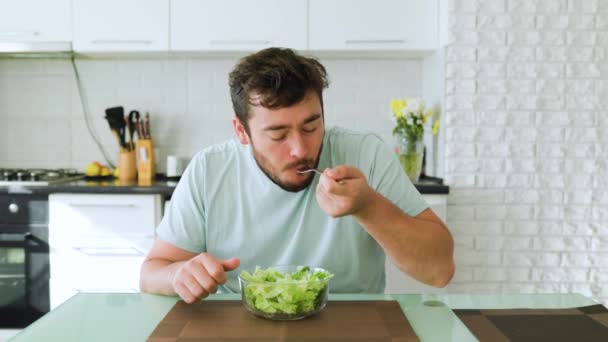 一个沮丧的年轻人坐在椅子上吃沙拉 用香草腌制和咀嚼蔬菜 前面的景色看不见眼睛 停止饮食 — 图库视频影像