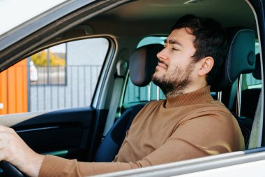 Direksiyondaki adam, kahverengi kazak giymiş. Sessiz insanlar, araba şoförleri.