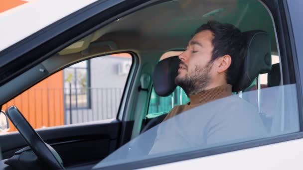 侧面看 一位年轻的男性司机坐在方向盘前休息 疲倦地把头靠在座位上 在路上呆很长时间对司机不好 疲惫和一个留着胡子的男人 — 图库视频影像
