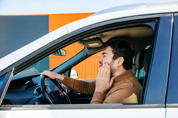 Caucasian disturbed bearded chauffeur man he has toothache in the interior of a car. male person suffering annoyed and stressed middle age people, profile view, in the car, healthcare and
