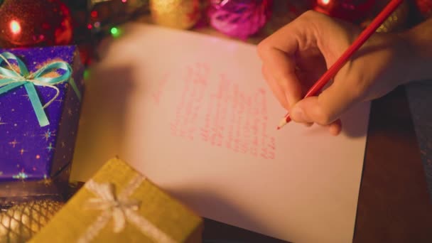 圣诞节的时候 无法辨认的人把什么东西用红色写在白纸上 旁边躺着一个装有礼物的蓝色盒子 有选择的重点 — 图库视频影像