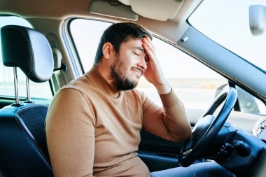 Arabada oturan genç bir adamın yüzünde acıma ve keder duygusu. Sakallı sürücü arabada oturuyor ve üzgün. İnsanlar ve duygular.