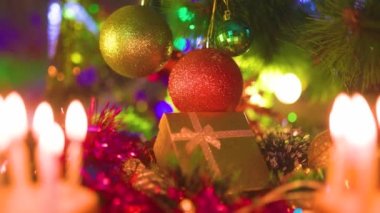Noel süslemeleri farklı renklerde hediye kutusunun yanında asılı. Tinsel topların altında yatar ve çelengin ışıklarından parıldar. seçili odak.