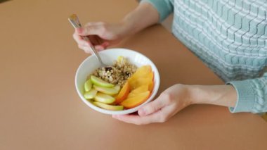 Manzara çiğ yulaf, mango doğal kase ve kaşık kadınların elinde. Sağlıklı vejetaryen kahvaltı kasesi elleri dişi, meyveler, tahıl yakın. Vegan, vejetaryen, temiz yemek, diyet, kilo verme konsepti