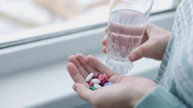 Aşırı dozda ilaç, tablet, elinde tanınmayan haplar, diğer elinde bir bardak su. Sağlık tehlikede. İnsan hastalıkları, zihinsel hastalıklar, intihar.