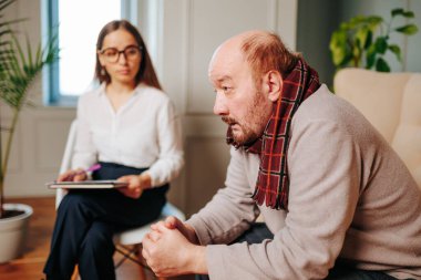 Psikoterapist, psikoterapi seansı melankolisi konusunda uzman psikolog konsepti olan depresyondaki kel erkek hasta sağlık hizmetleri konseptiyle konuşurken notlar alıyor.,