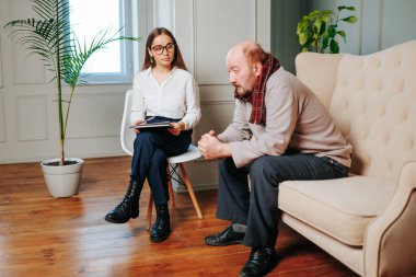 Yaşlı, kel bir adam bir danışman toplantısında, elinde dosya olan psikiyatrist ofisinde mutlu bir hastayla konuşuyor. Stres, kıdemli hüsran ve yaşlı adam, emeklilik sorunu, düşünceli erkek.,