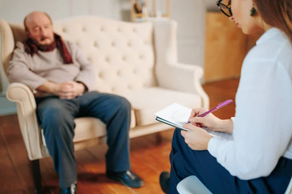 senior distressed man talking to psychologist during therapy session, indoors. Help, support, ptsd, health and harmony concept, friendly conversation, physician understand, conversation elderly,