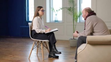 Kadın, akıl sağlığı kliniğinde profesyonel yardım Amerikalı erkek hasta terapi sonuçlarını danışman, psikoterapi seansı, yaşlı kel adam, mutsuz, üzgün psikoloğuyla konuşuyor.,