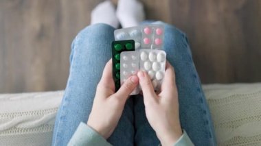 Close up tablets of different orientations in hands of unrecognizable person who is being treated for something. Antibiotics, enzymes, analgesics. Man in jeans.